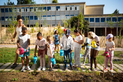 enfants en ligne qui arrosent de la terre